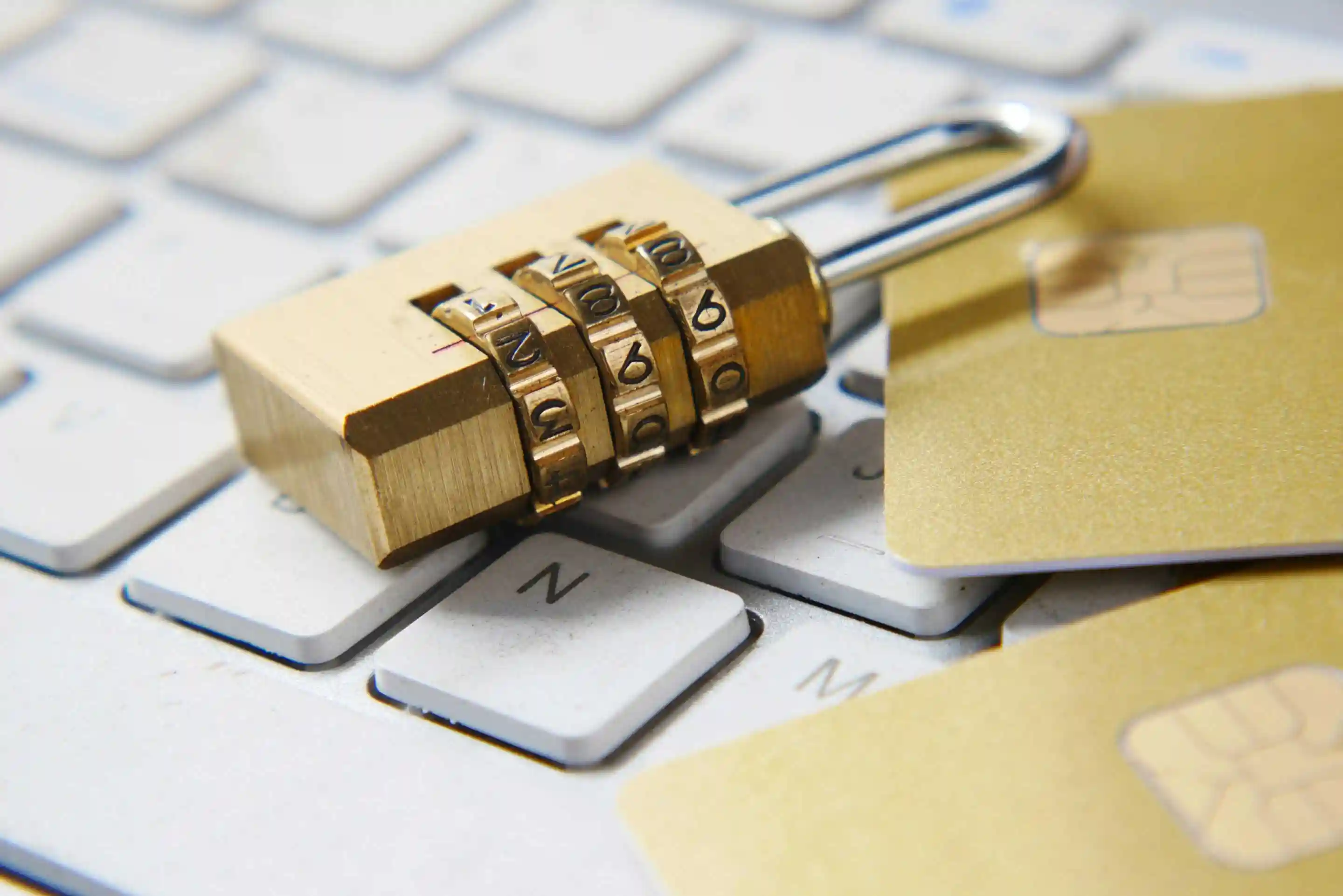 Background: combination padlock and gold credit cards on a computer keyboard, symbolizing online security and data protection